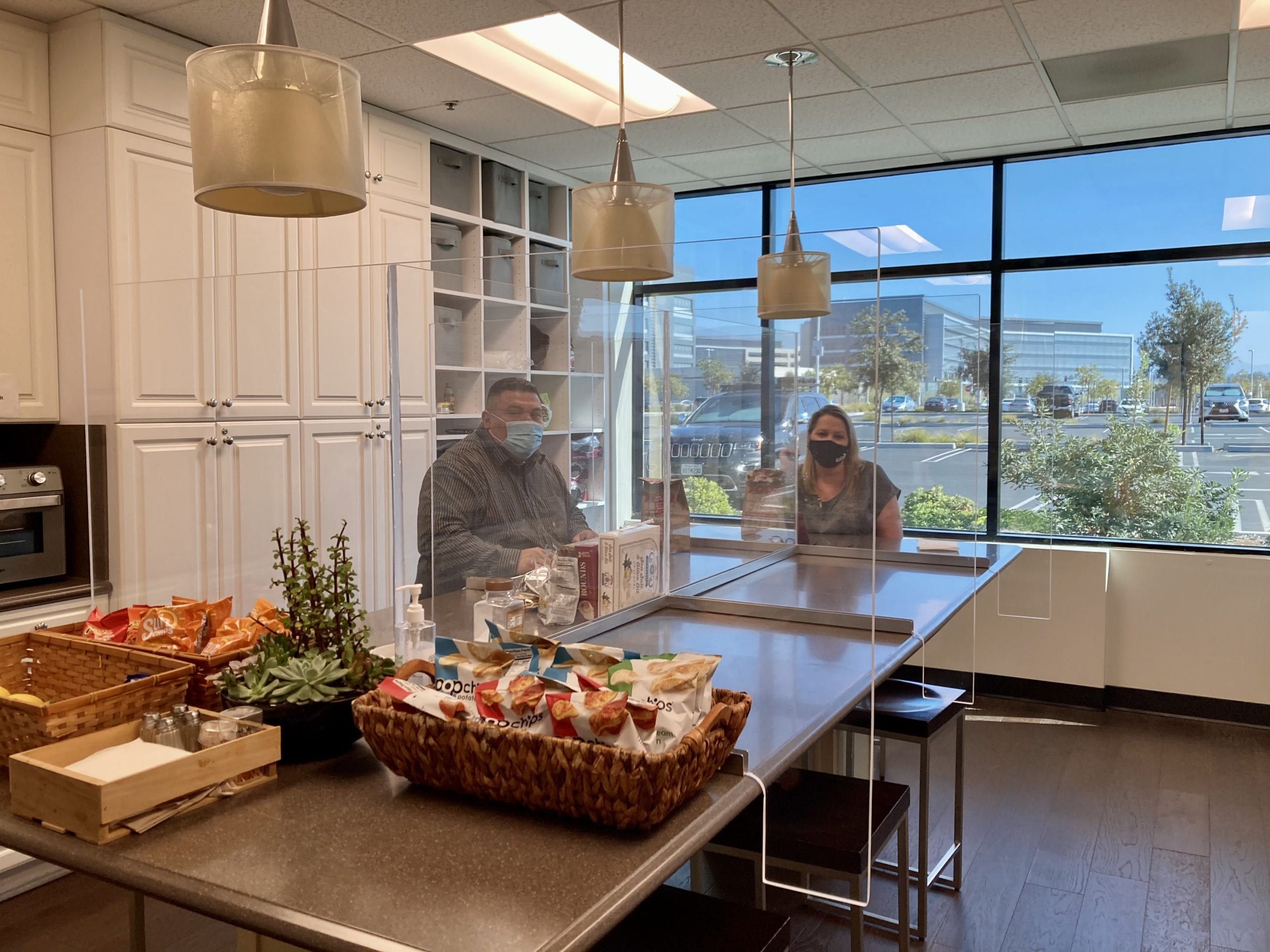 plexiglass partitions allow two employees to collaborate in kitchen